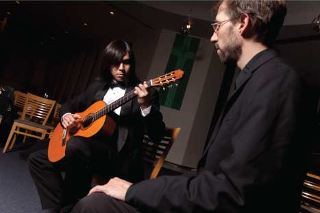 student playing the guitar for an instructor
